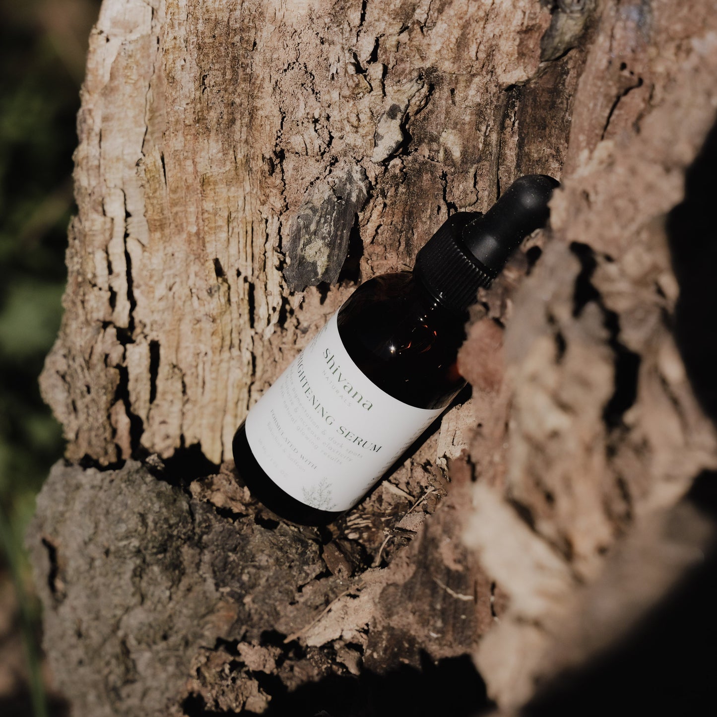 Skincare serum bottle with dropper on a textured wooden surface